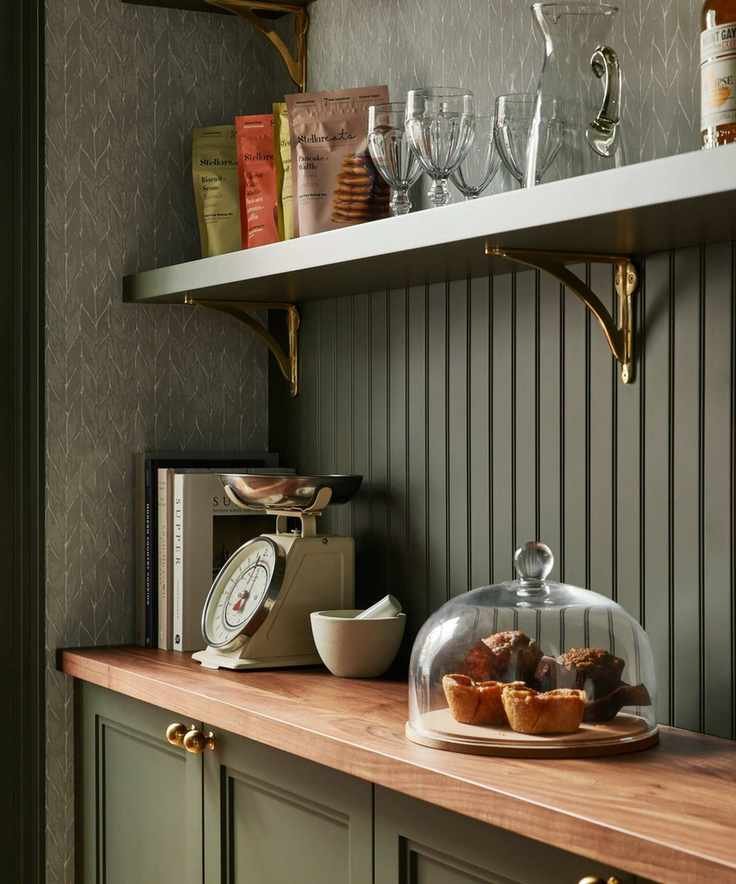 a mid green painted pantry with beadboard walls, wallpaper, and a wooden counter beneath open shelving