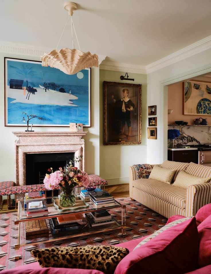 Layered living room featuring a mauve and magenta geometric rug, glass two-tier coffee table, striped sofa, and collected wall art