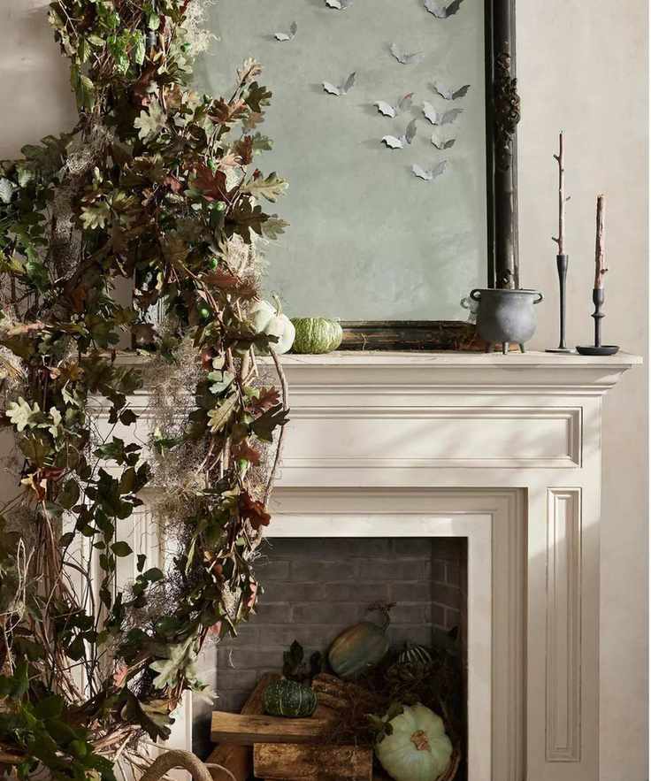 Neutral fireplace mantel filled with pumpkins and firewood with foliage