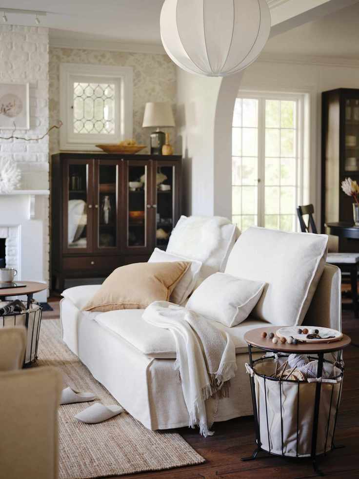 white and neutral living room with white modern style couch, wood and metal storage side tables, neutral rug, taupe cushions, mahogany style display unit