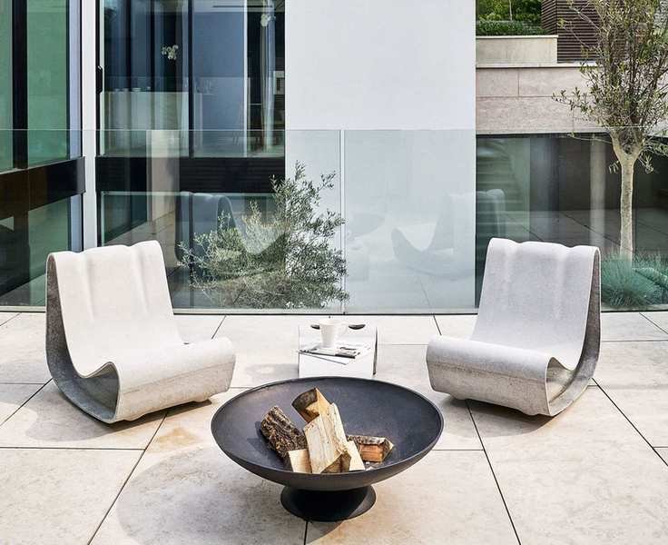 Sculptural metal chairs in front of a fire pit.