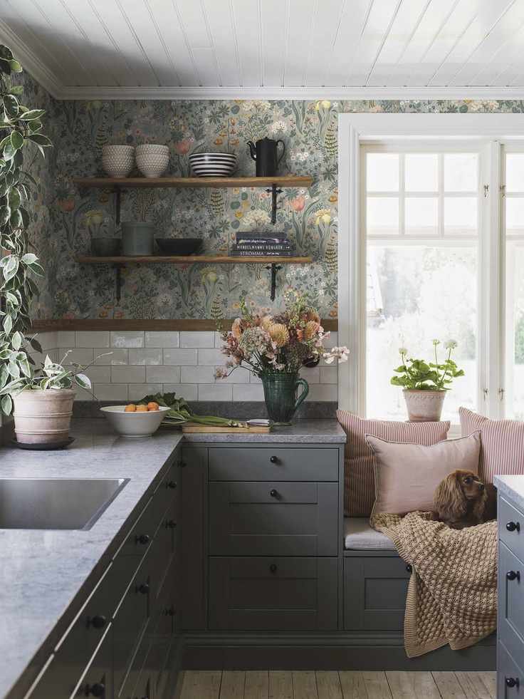 light green wallpaper in Scandi style kitchen featuring dark gray cabinets a window seat and a dog
