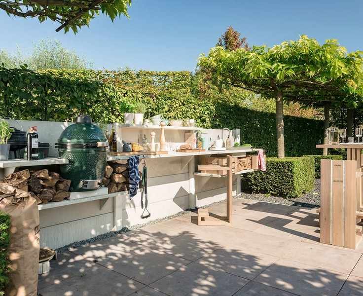 A big green egg grill in a wooden outdoor kitchen