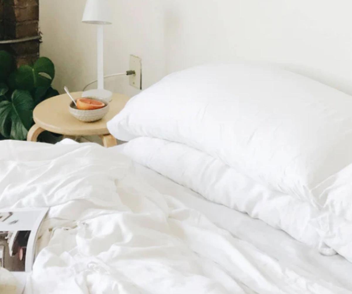 Cozy Earth Silk Pillows on a bed beside a nightstand.