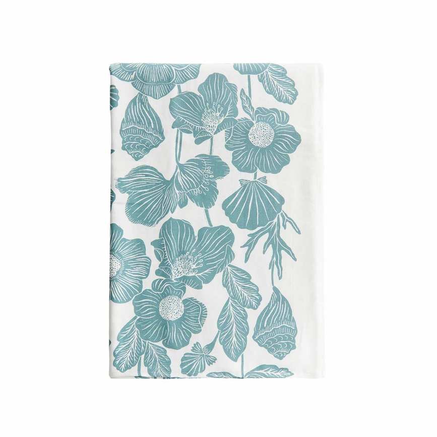 A folded white tablecloth with a teal blue shell, coral, and flower pattern