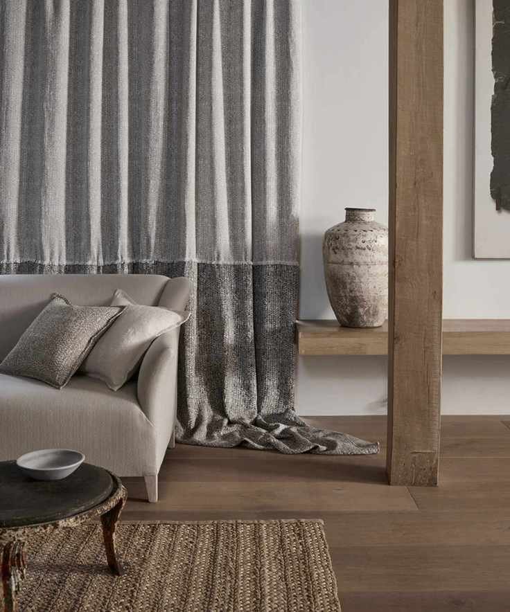 silver colored sofa with sustainable upholstery in front of grey two tone fabric and wooden floors