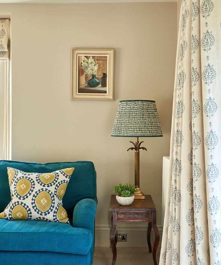 The corner of a sitting room with a bright blue sofa and brass table lamp