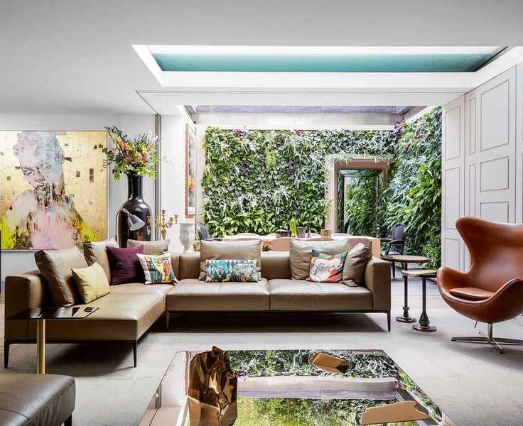 Large open living room with leather egg chair and leather sofa, mirrored coffee table, and outdoor-indoor courtyard