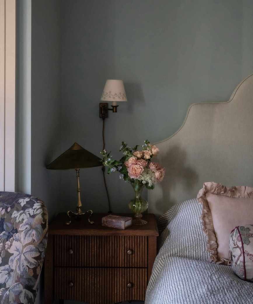 bedroom with gray-green walls and nightstand with flowers
