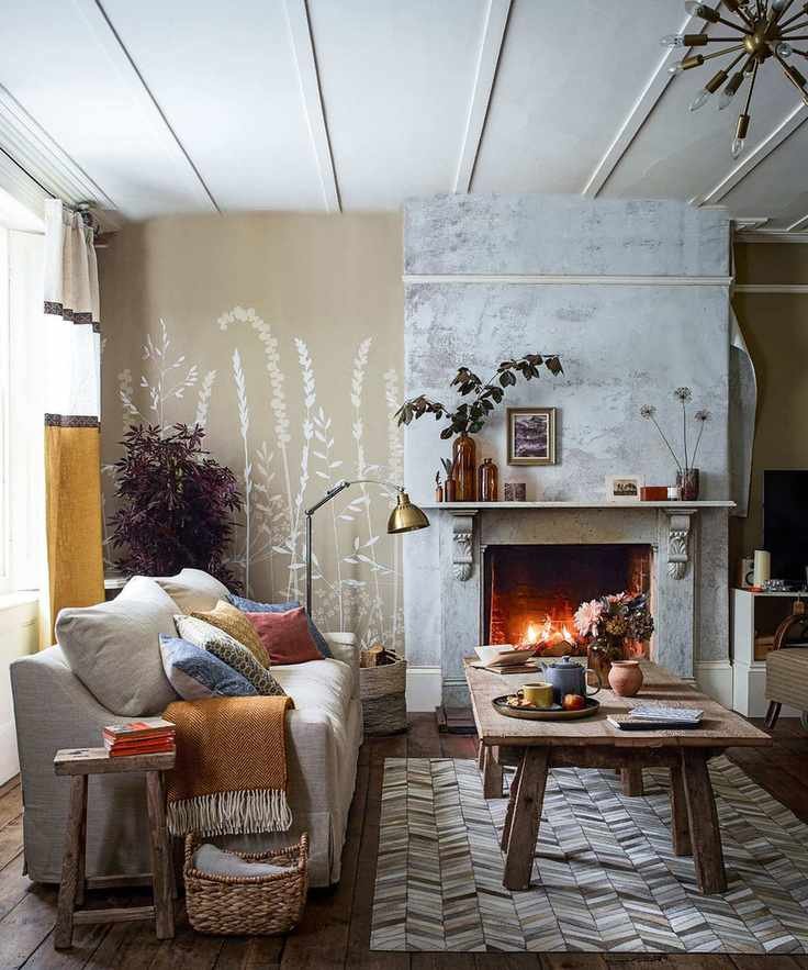 A modern living room featuring a cozy sofa with colorful cushions beside a lit fire.