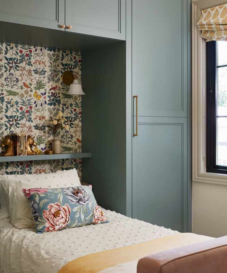 a little girls' bedroom with custom blue painted joinery, a single bed, and a butterfly and floral printed wallpaper