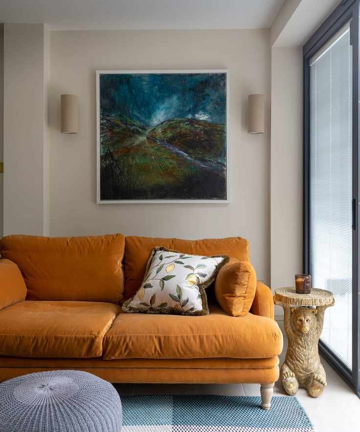 orange velvet sofa with decorative side table and artwork above