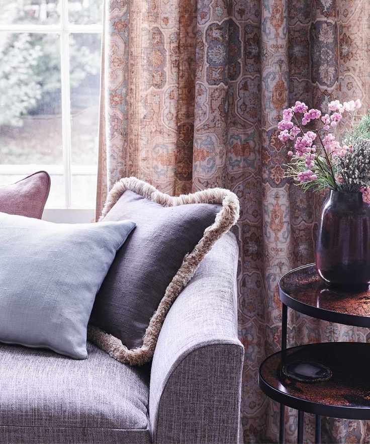 A living room with a purple sofa and a nested table with flowers.