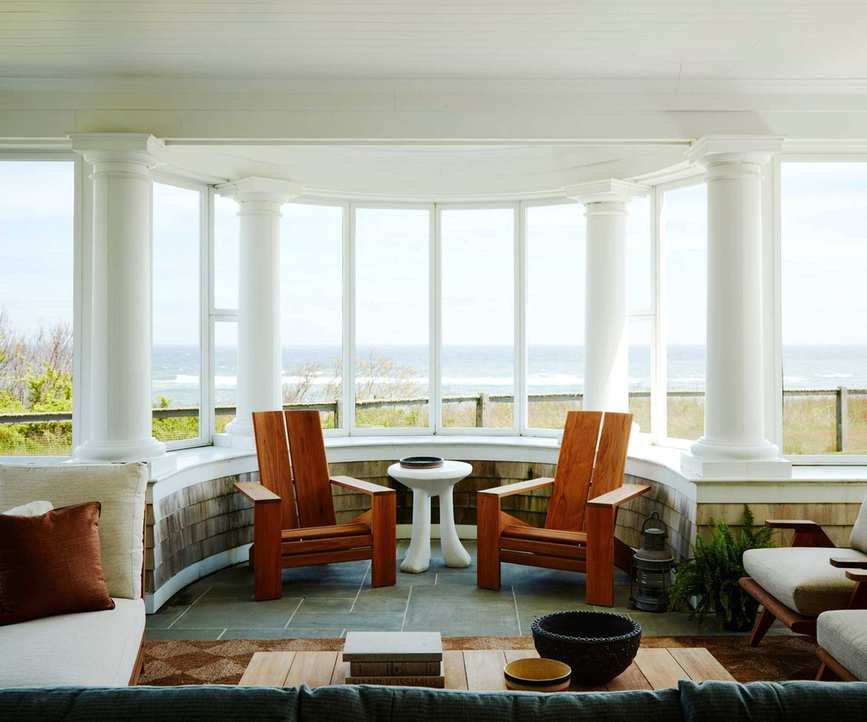 Front porch with columns, wood chairs, coffee table and sofa looking out onto seat