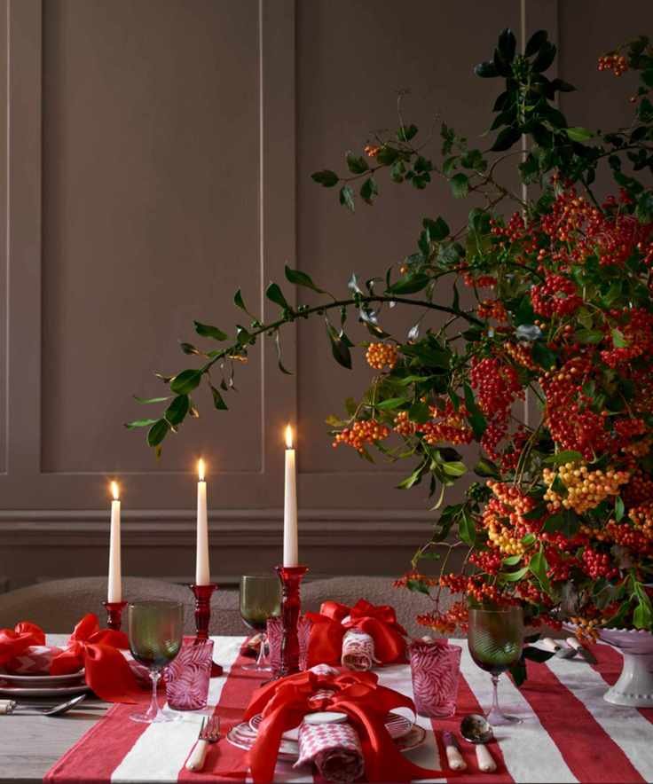 Fall tablescape with red and white striped tablecloth, seasonal berries, red candlestick holders and taper candles