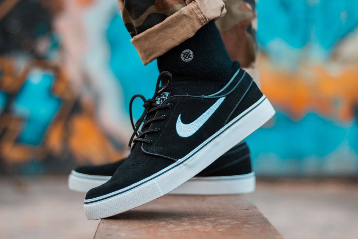 Black Nike sneaker worn on foot against a colorful background
