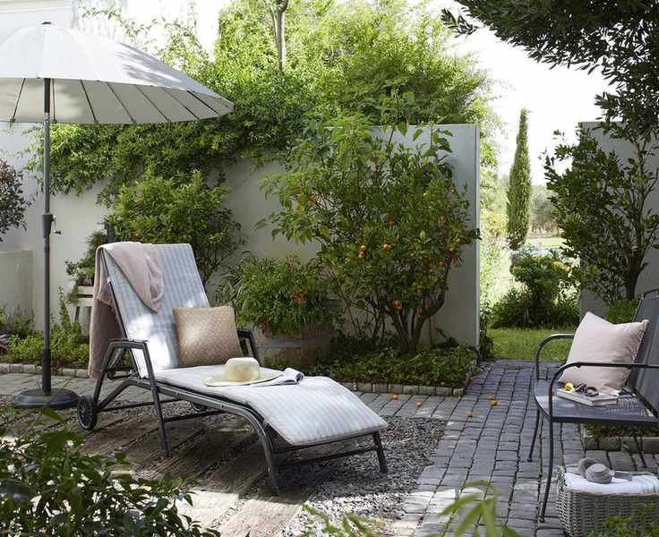 A cozy garden setting with a sun lounger and climbing plants.