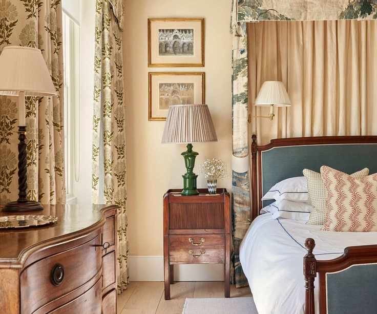 Vintage bedroom with printed drapes, wooden side table, vintage lamps and wooden bed