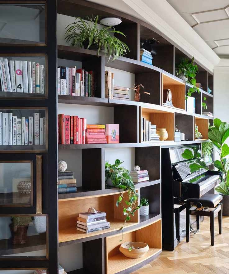 modular open shelving with books, plants, and an upright piano
