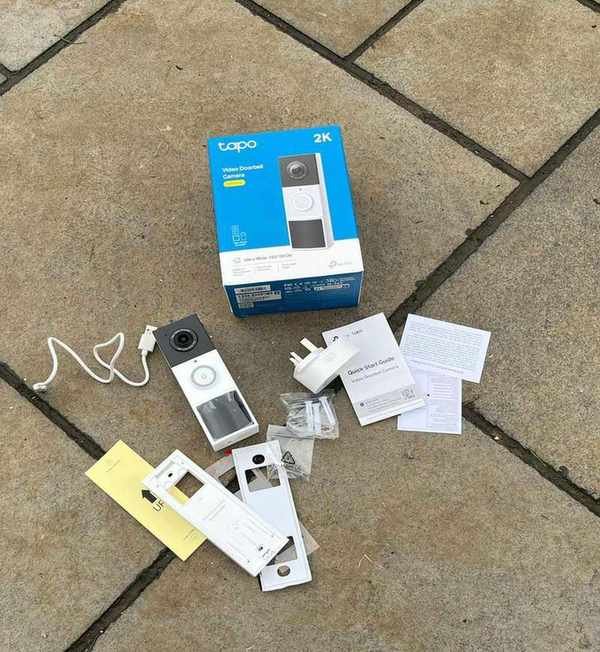 Every part of the Tapo D210 Video Doorbell kit unboxed on tiled concrete floor.