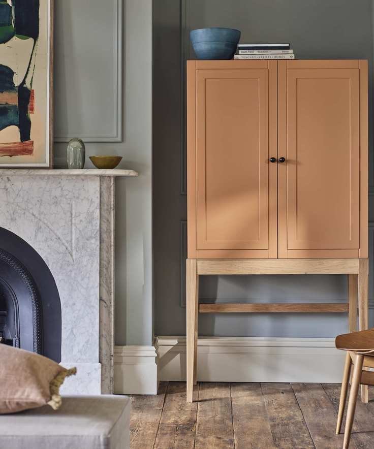 colors not to paint your furniture, living room with grey walls, coral painted cabinet, marble fireplace, wooden floorboards, artwork