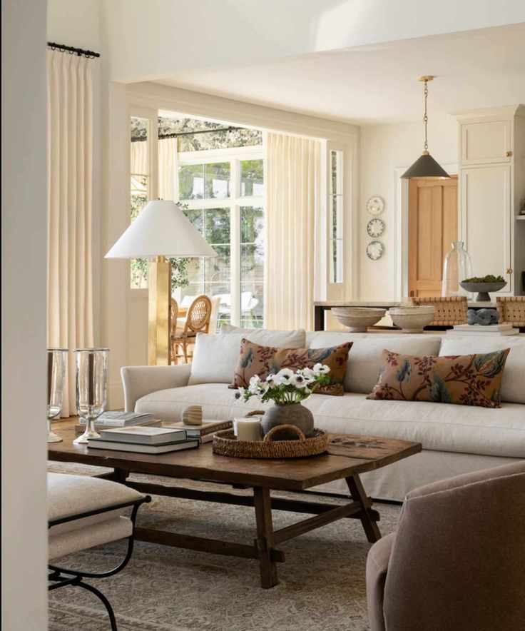 neutral living room open plan kitchen with neutral couch, wooden coffee table, and earthy floral cushions