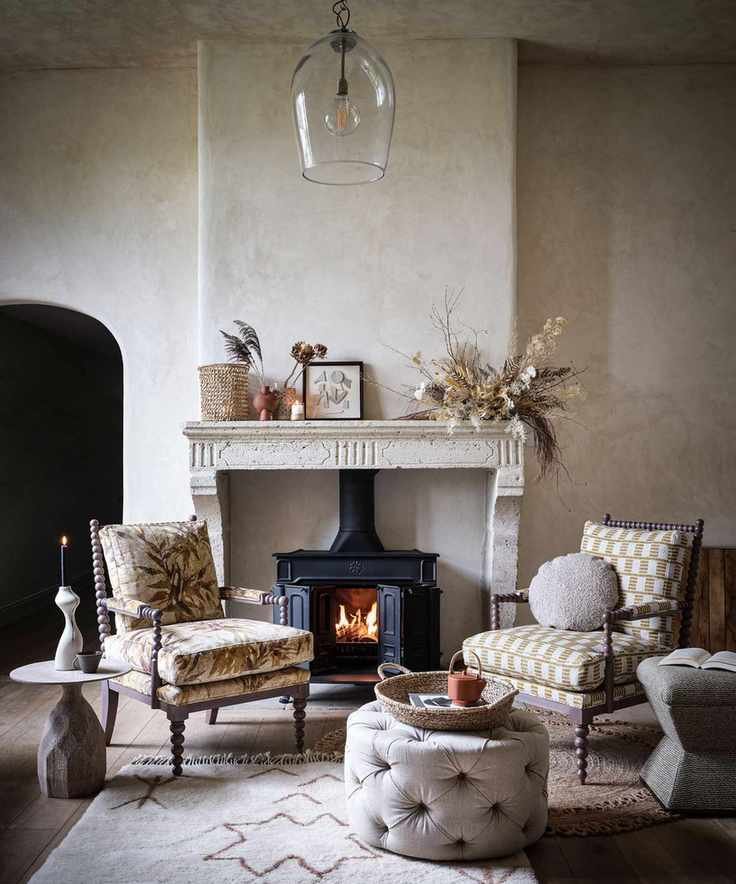 A cozy living room featuring a lit fireplace with a marble mantle and wooden floor.
