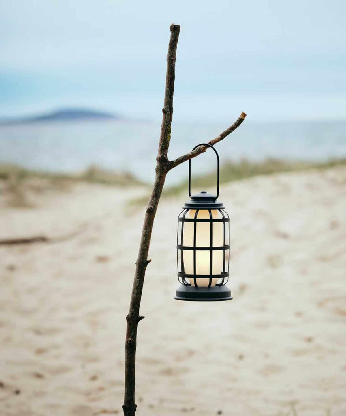 a lantern hanging from a stick on a beach
