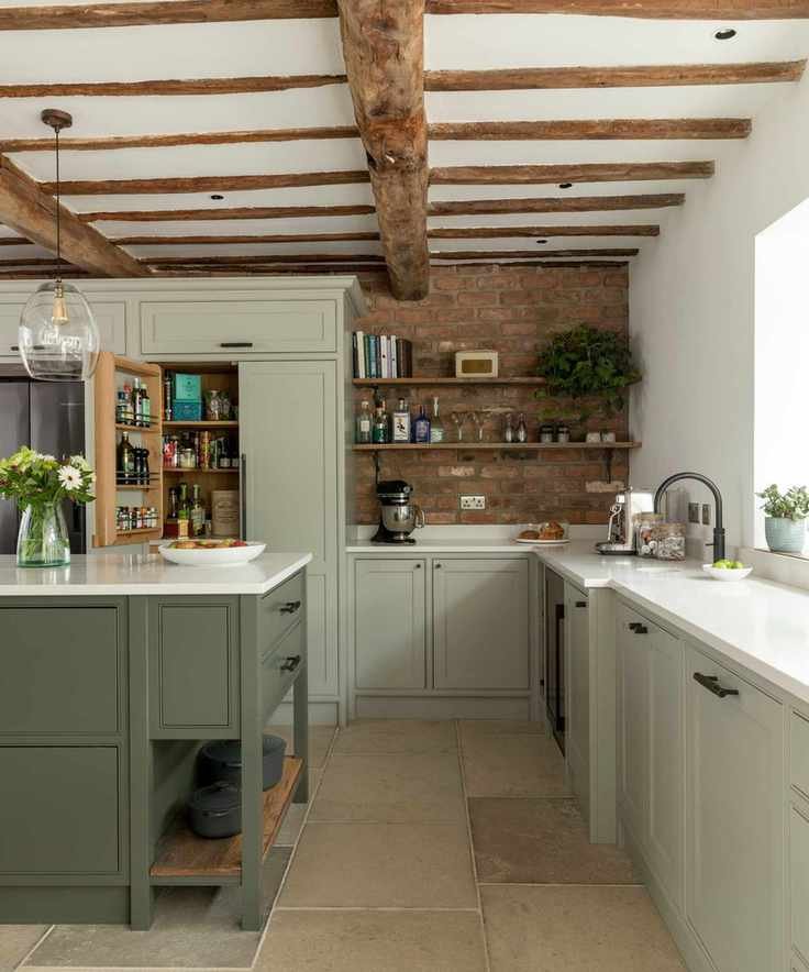 A khaki kitchen island contrasting with light sage cabinets