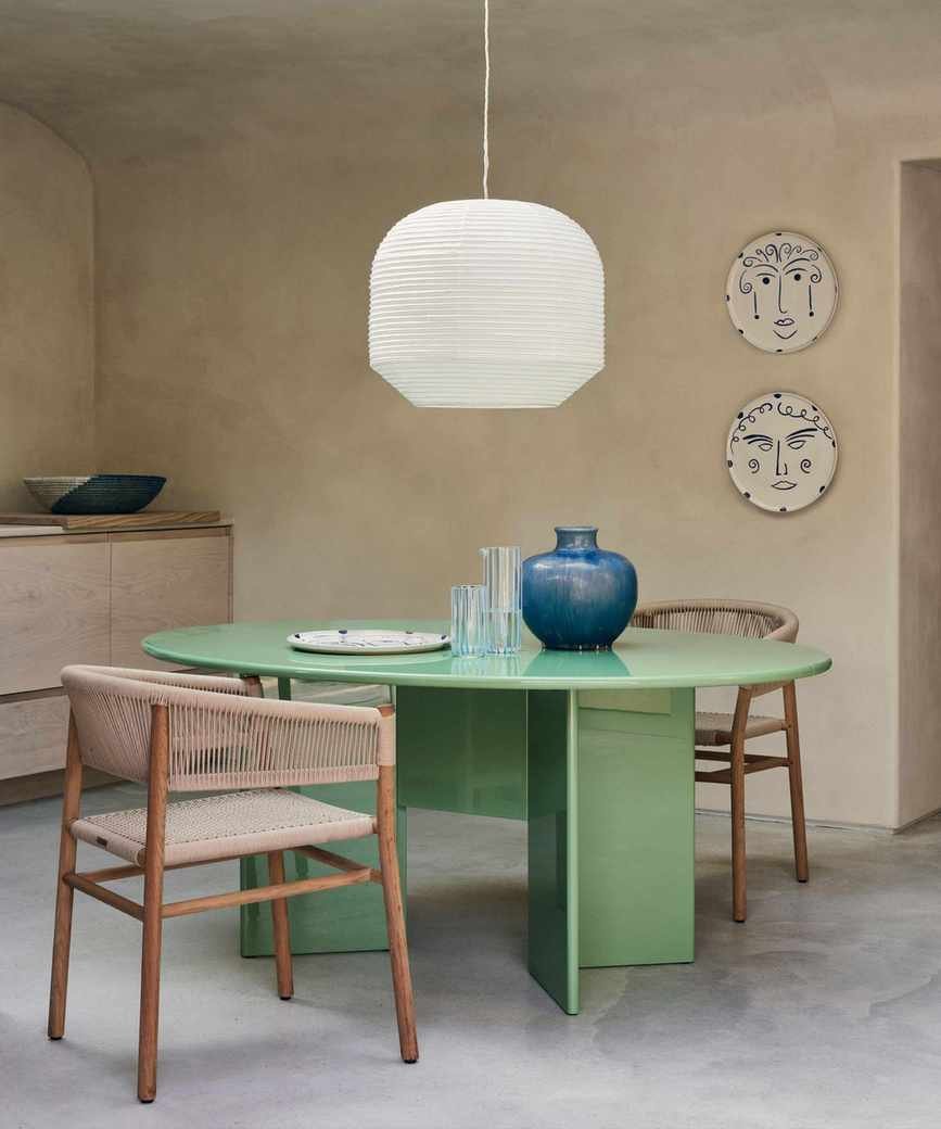 Neutral dining area with a mint green rounded table and wooden chairs.