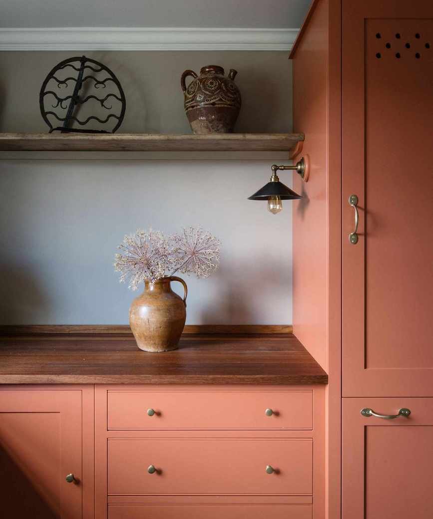 Red kitchen cabinets with white wall and shelving for objects