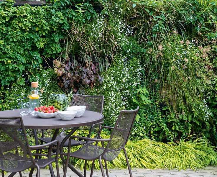 Outdoor dining area with a living wall behind