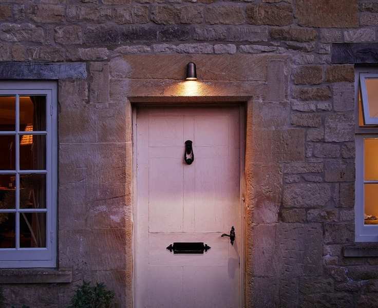cottage with pale pink front door, singular lamp above the front door