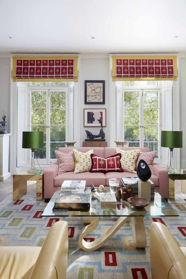 A small living room with two large windows, modern furniture and a geometric rug.