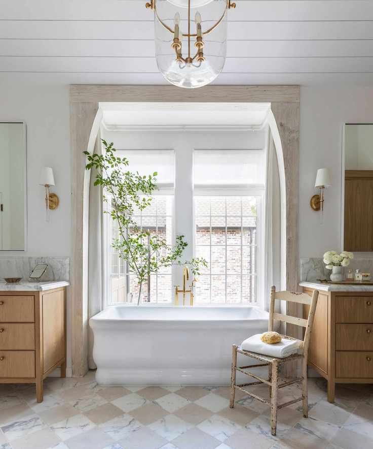 A luxury bathroom with an alcove bathtub fitted in a bay window framed by wooden beams