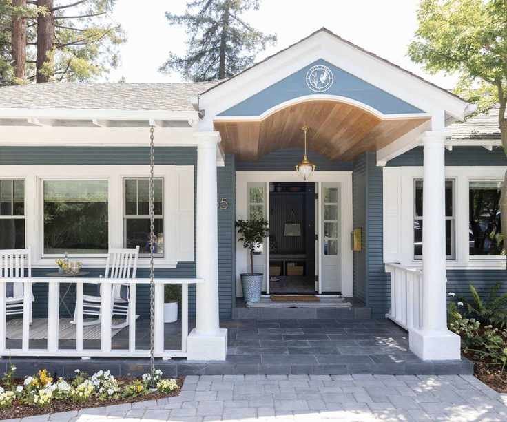 Traditional house with columns and white fence, porch with two rocking chairs and front door