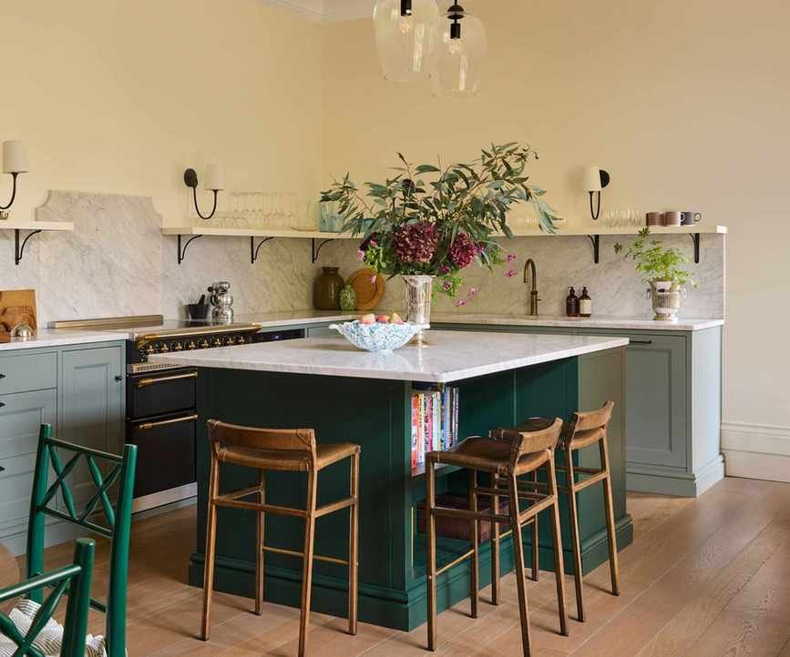 A green kitchen with a dark green island