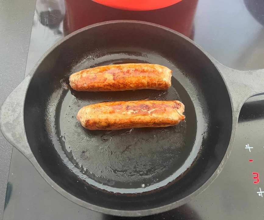 Golden brown sausages in a skillet.